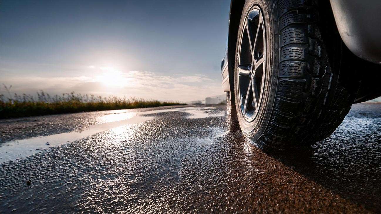 Primer plano de un neumático sobre carretera mojada
