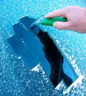 Alguien limpiando el hielo de un parabrisas con una rasqueta