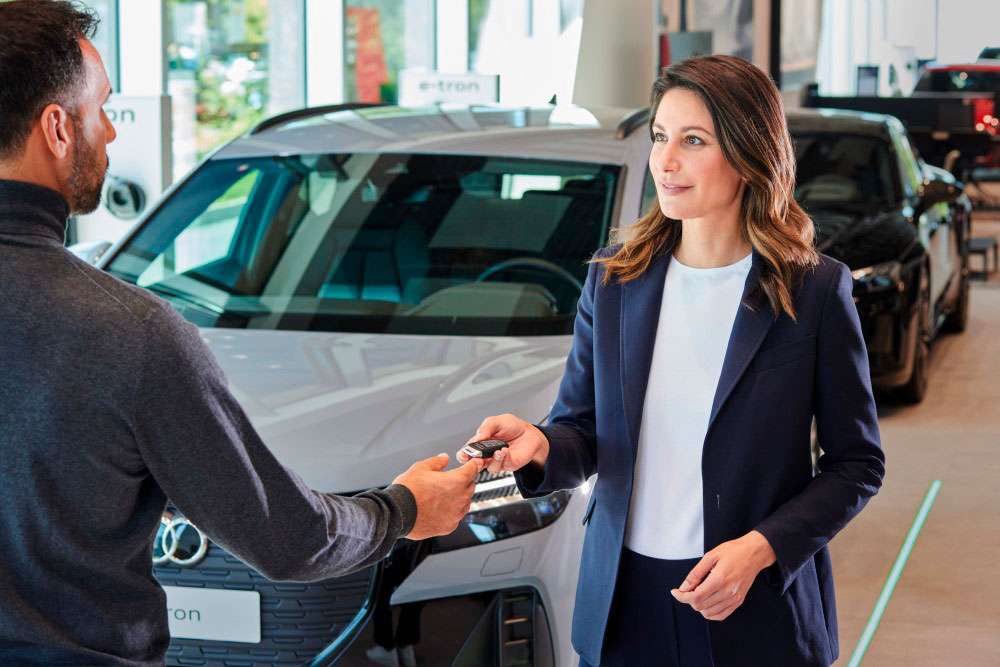 Vendedor entregando llaves de Audi a una mujer