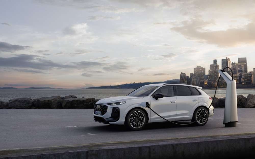 Audi Q3 e-hybrid conectado a una estación de carga con una ciudad de fondo