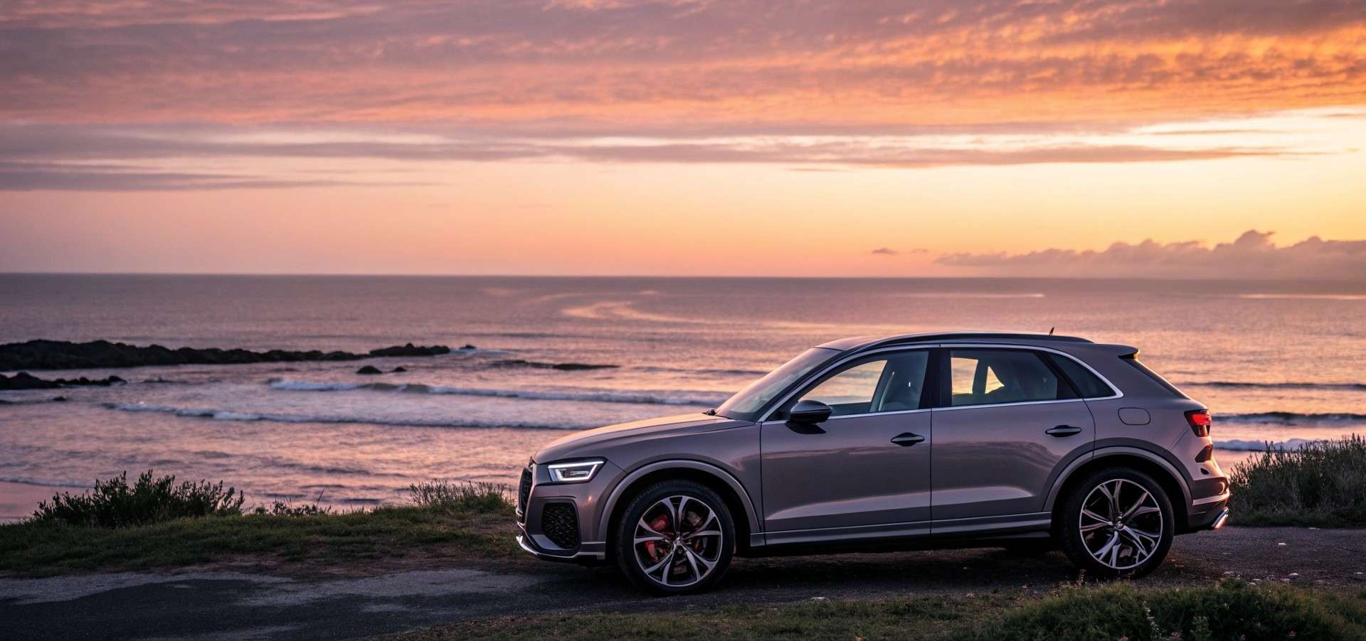 Audi Q3 frente al mar en una puesta de sol