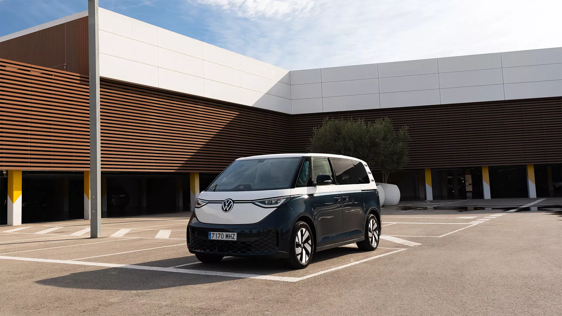 Volkswagen ID Buzz Cargoestacionado en un aparcamiento vacío frente a un edificio con fachada de madera y gris