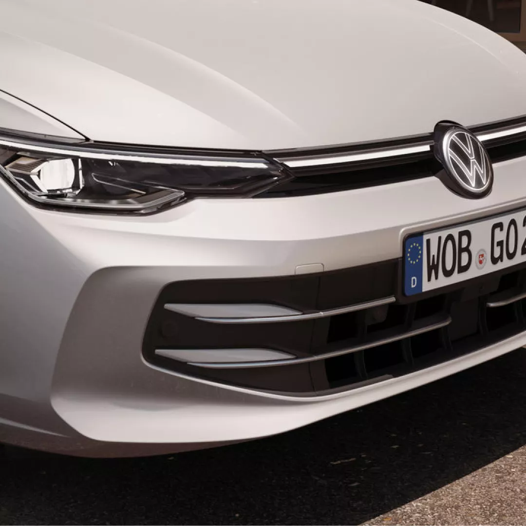 Frontal de un automóvil Volkswagen Golf blanco con el logotipo de la marca y la matrícula europea