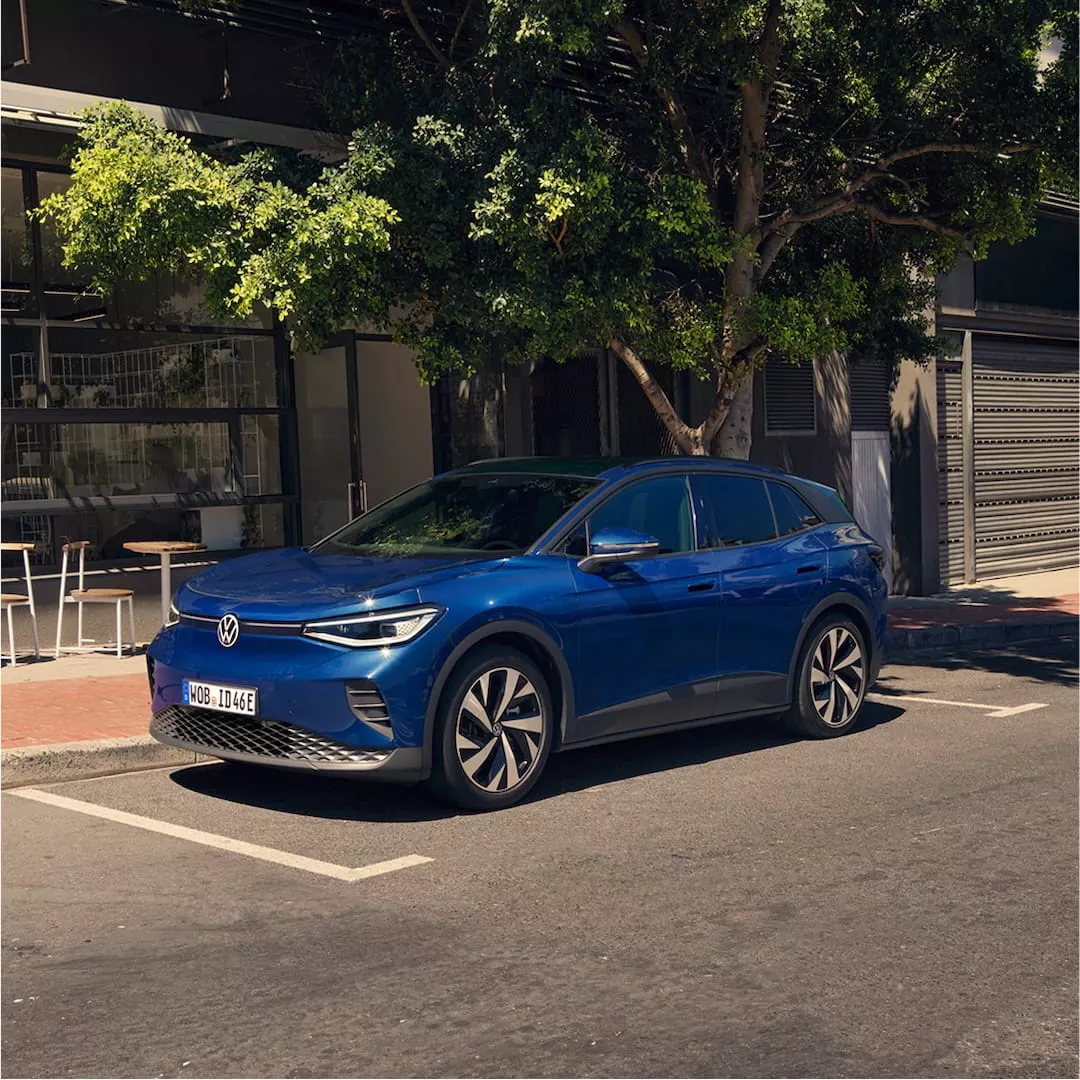 Vehículo SUV eléctrico Volkswagen ID.4 de color azul oscuro estacionado en una calle arbolada