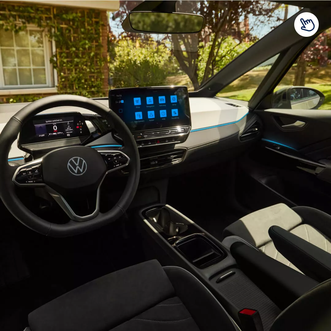Interior de un vehículo Volkswagen ID.3 con un panel de control digital en el centro, volante con logo y asientos de cuero negro. Destacan los detalles de diseño y tecnología moderna del automóvil.