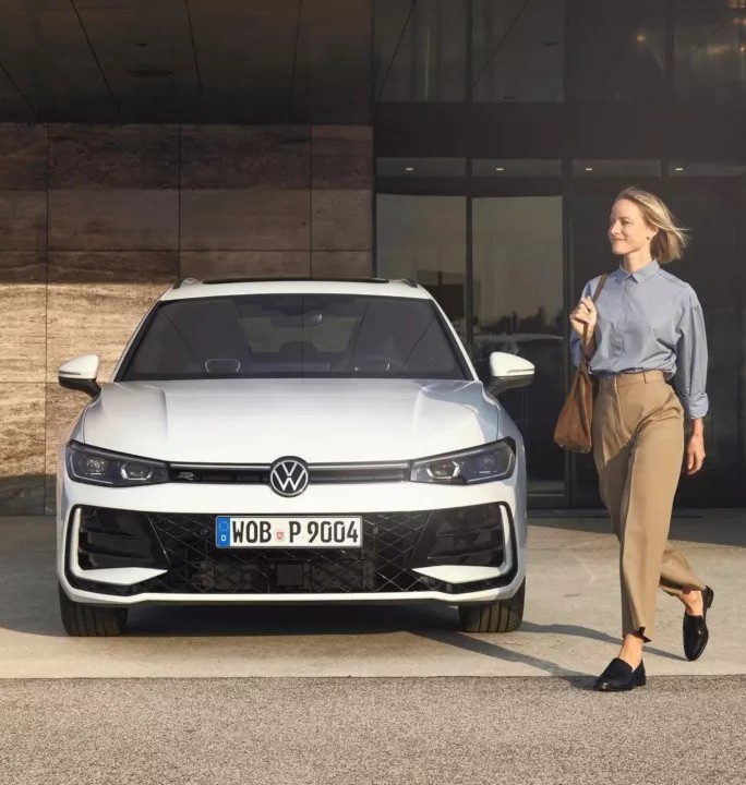 Mujer caminando junto a un Volkswagen ID.3 plateado estacionado frente a edificio