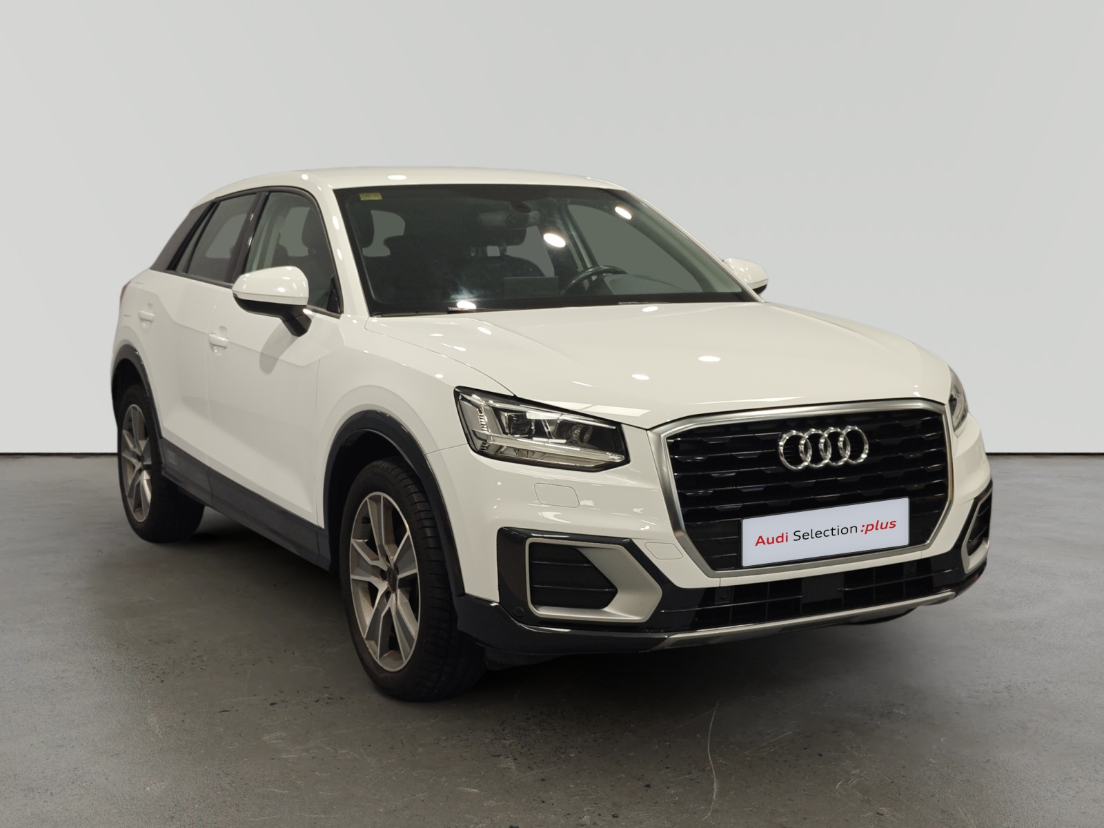Audi Q3 blanco estacionado en interior con letrero Audi Selection plus