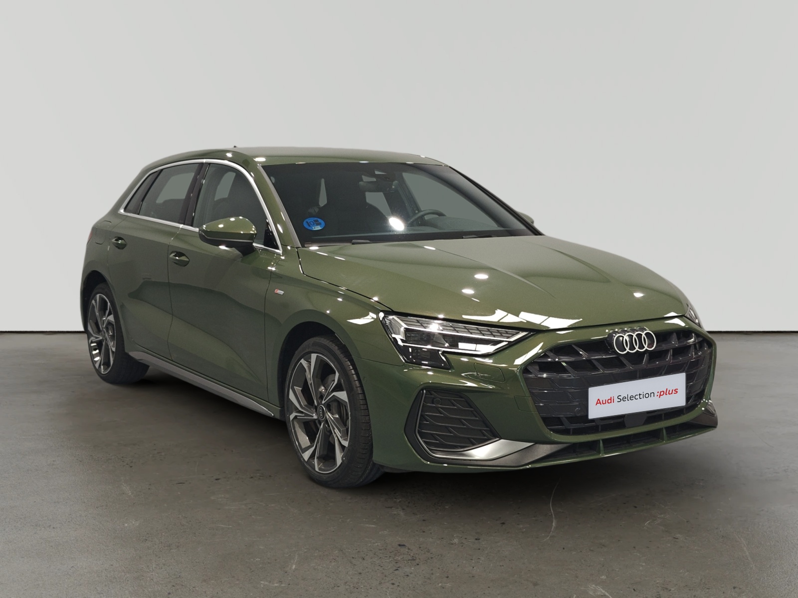 Audi A3 verde estacionado en interior con placa de selección plus