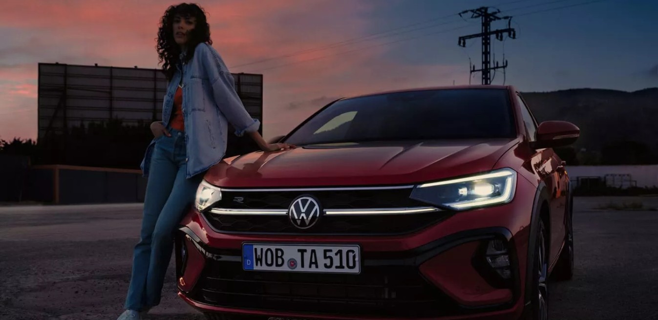 Mujer posando junto a un Volkswagen Taigo al atardecer