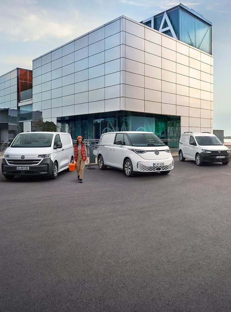 Tres Volkswagen Comerciales junto a edificio moderno con persona al frente