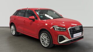 Audi Q3 rojo estacionado en interior con ruedas de aleación