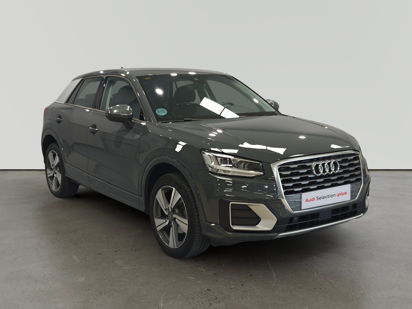 Audi Q3 oscuro estacionado en interior con letrero de selección plus