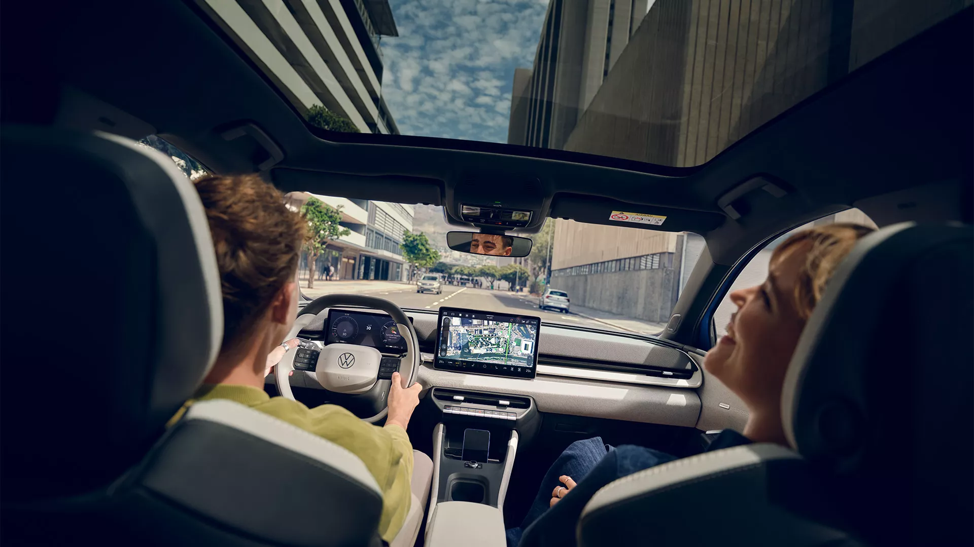 Dos personas en interior de Volkswagen ID. polo conduciendo por calle urbana