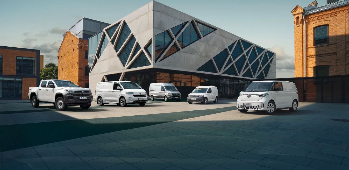 Cinco vehículos Volkswagen Comerciales Furgocasion estacionados frente a un edificio moderno