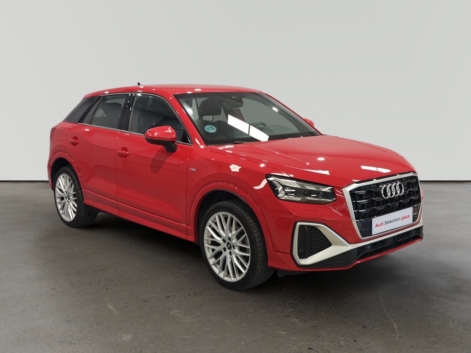 Audi Q3 rojo estacionado en interior con ruedas de aleación