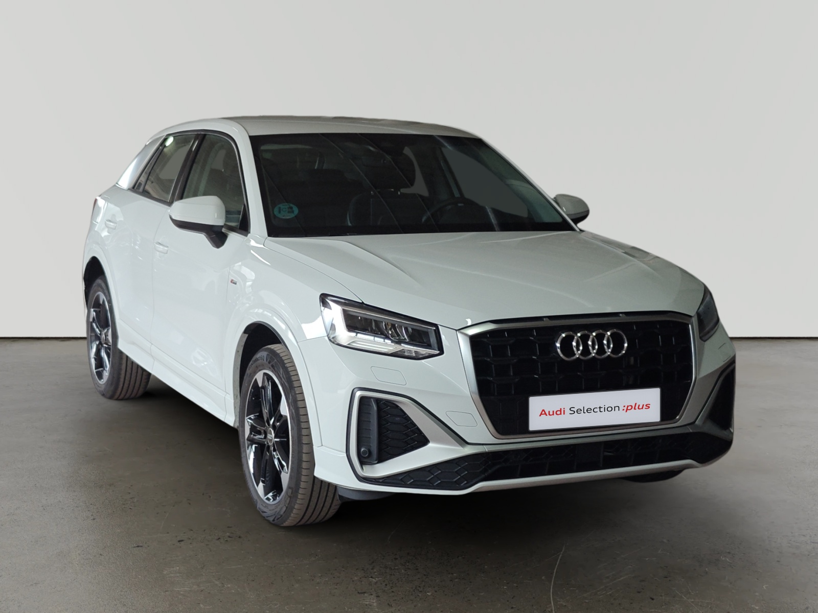 Audi Q3 blanco estacionado en interior con emblema Audi Selection plus