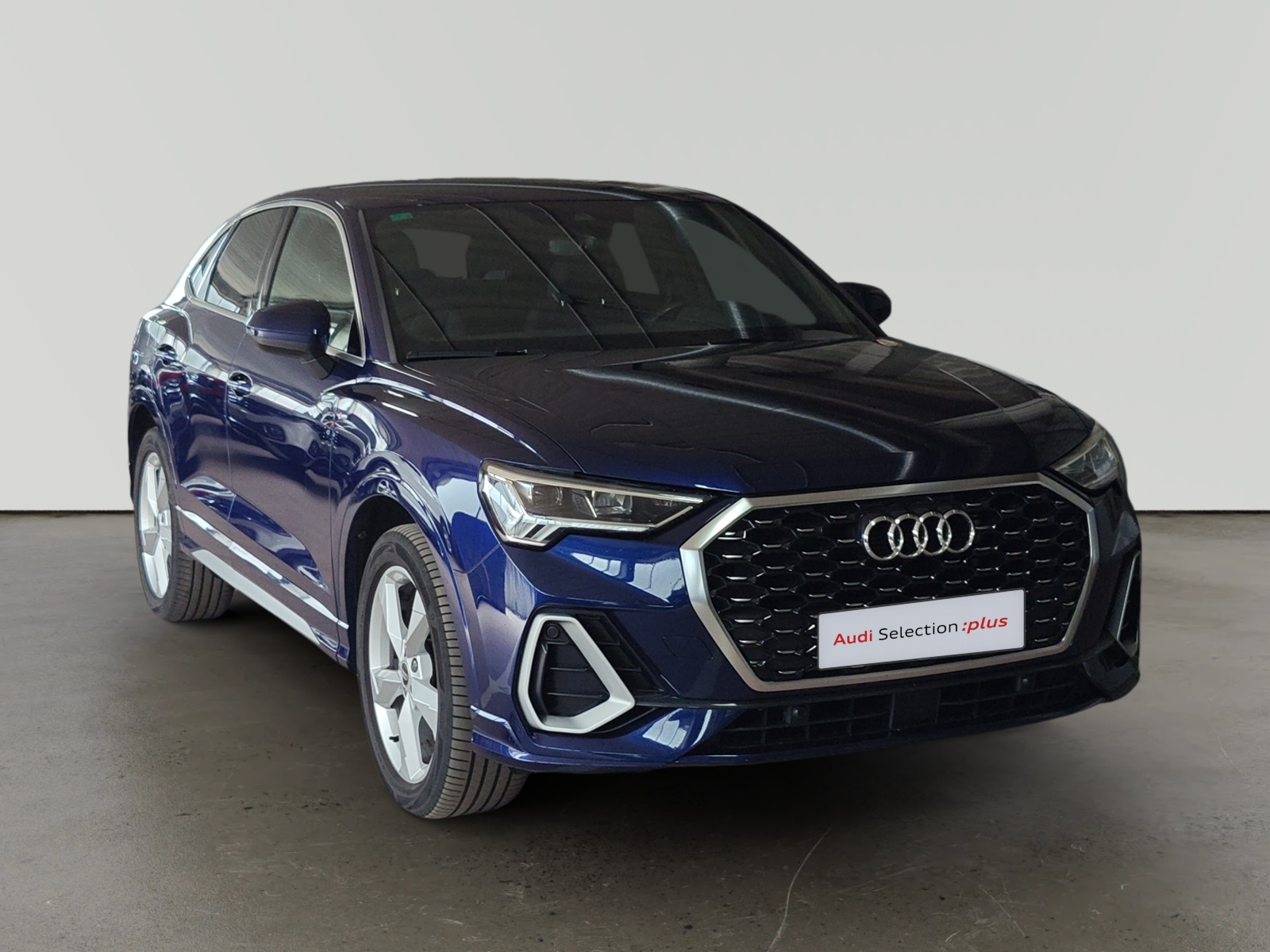 Audi Q3 azul estacionado en interior con letrero Audi Selection plus