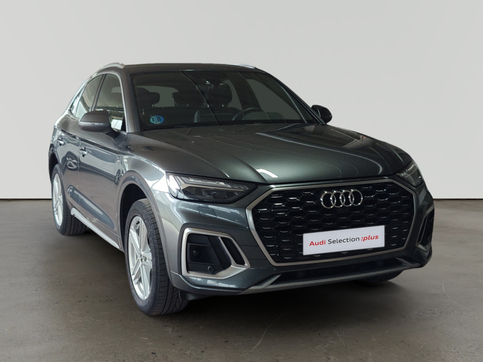 Audi Q3 gris estacionado en interior con letrero Audi Selection plus