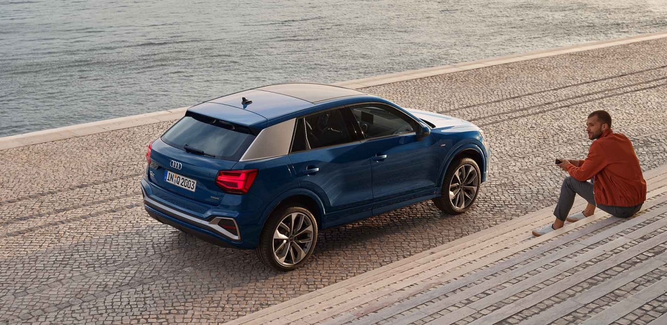 Audi Q2 Adrenaline edition azul estacionado junto al océano atlántico con persona observando
