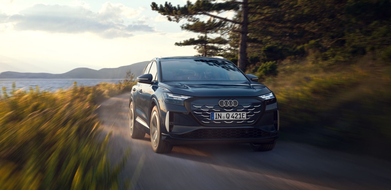 Audi Q4 e-tron eléctrico negro circulando por carretera junto al lago