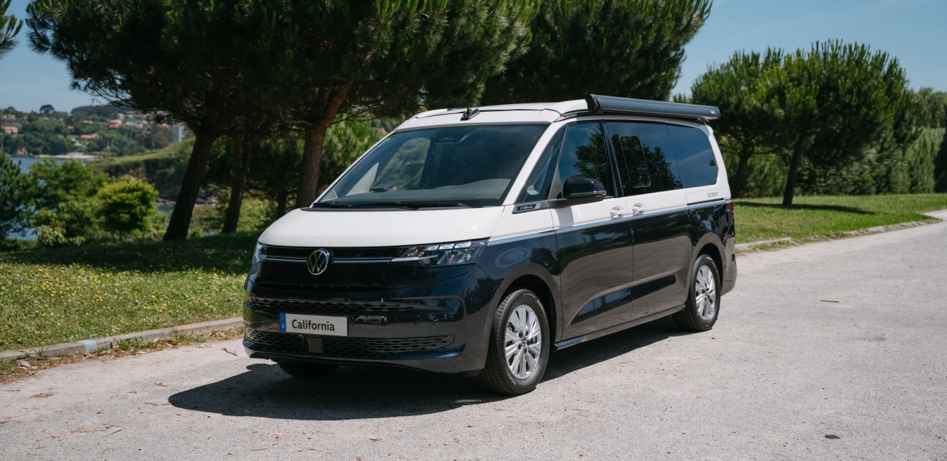 Volkswagen Nuevo California blanca y azul estacionada en camino rural junto al río