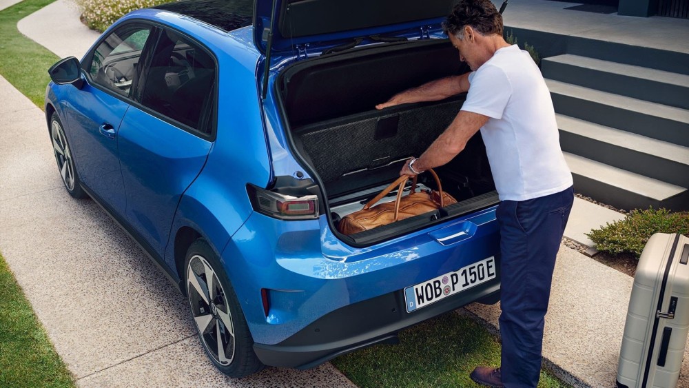 Hombre cargando bolsas en maletero de Volkswagen ID.Polo azul