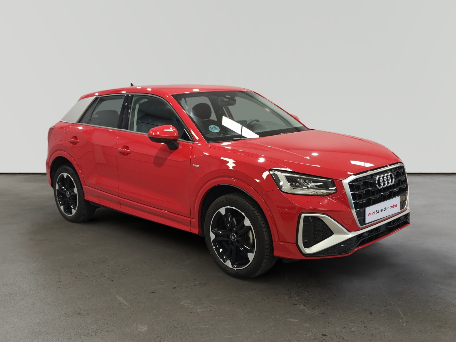 Audi Q2 rojo aparcado en showroom sobre fondo gris