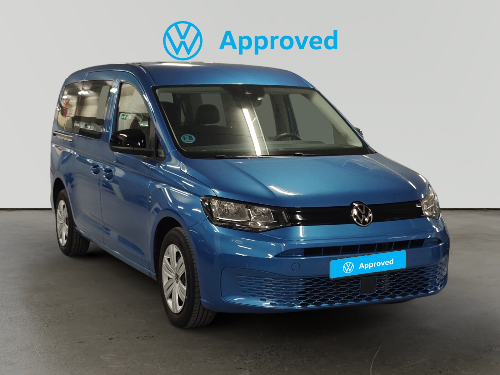 Volkswagen Caddy Maxi azul certificado Approved con distintivo de marca en fondo gris