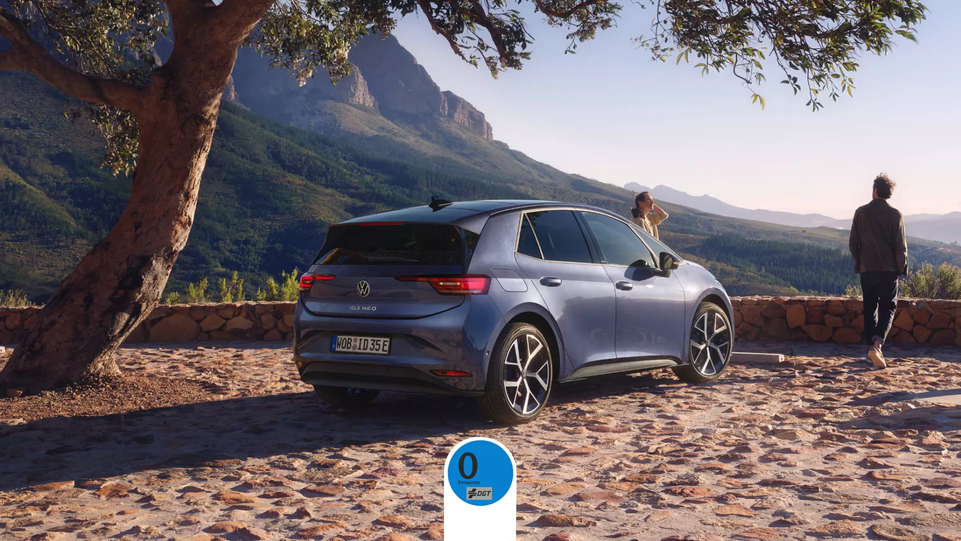 Volkswagen ID.3 neo azul estacionado bajo árbol frente a montaña