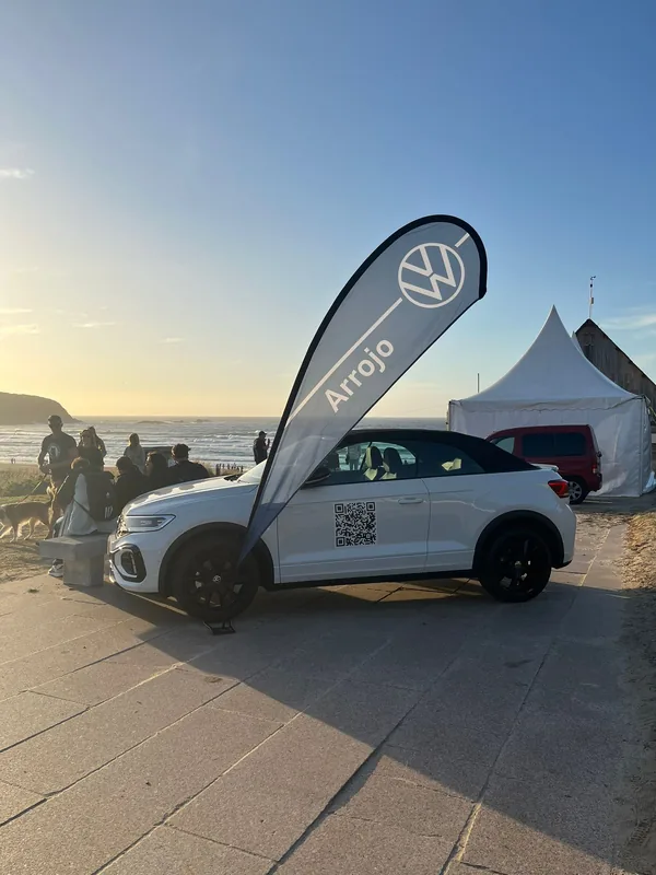 Volkswagen T-roc blanco en la playa con bandera de Arrojo y tienda de campaña en Pantín clais surf